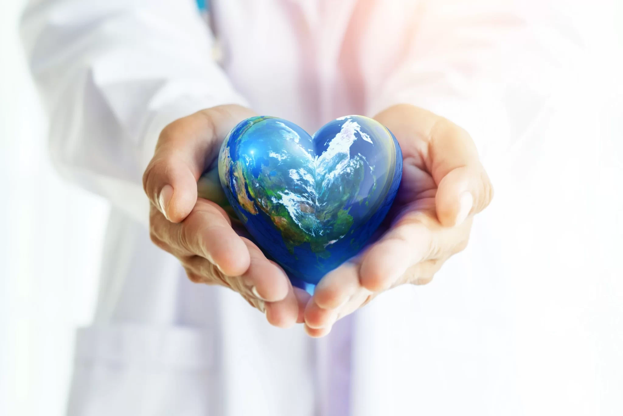 Doctor's hands carefully holding an Earth ball in a heart shape, symbolizing global sustainability and healthcare.